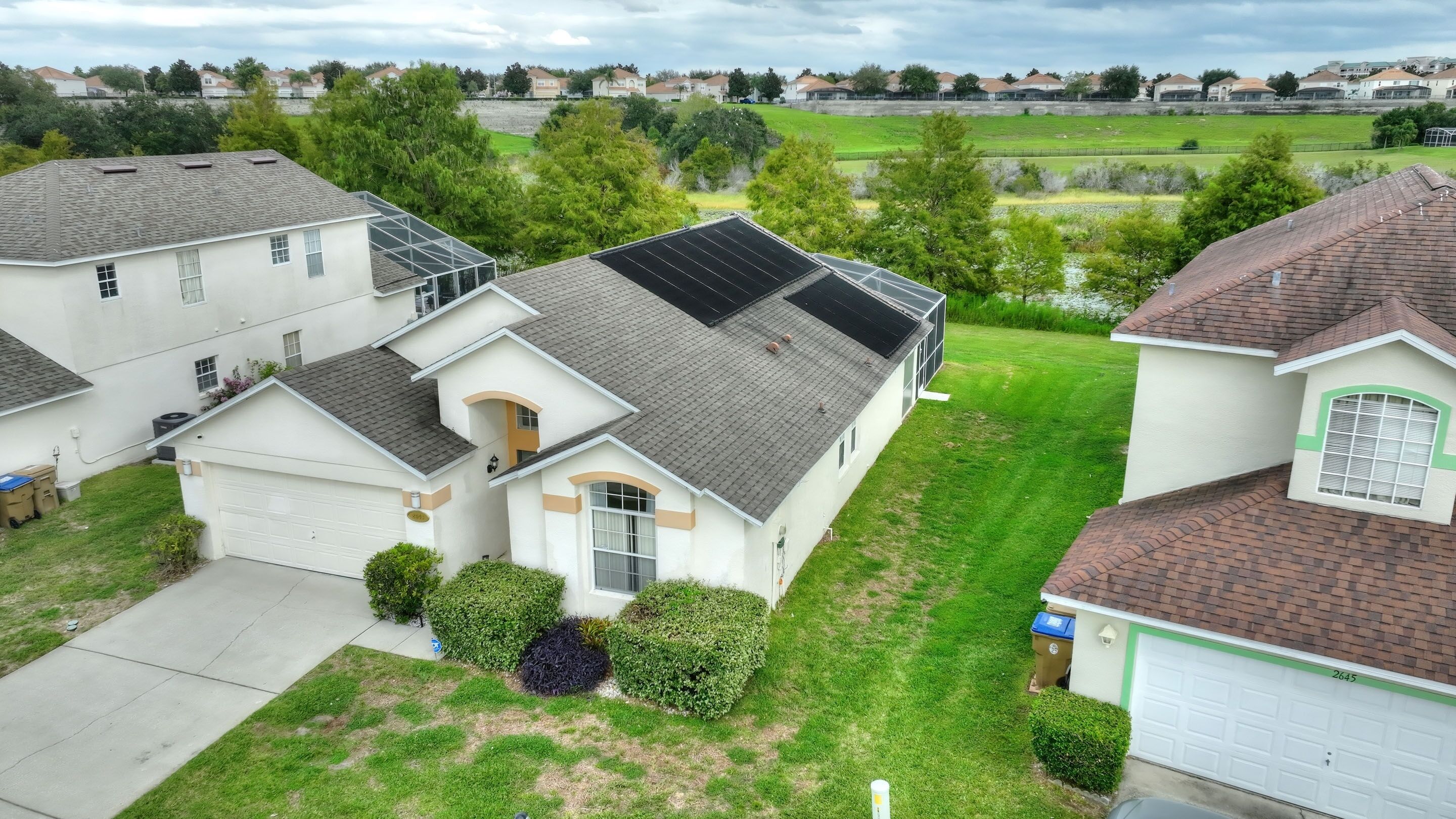 Une maison de plain-pied avec un garage, un petit jardin devant et un panneau solaire sur le toit.