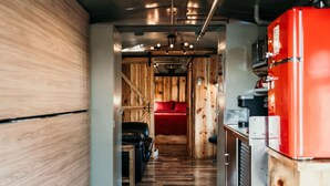 Un couloir étroit aux murs en bois, avec un appareil électroménager rouge sur le côté droit.