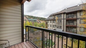 A balcony with a view of multi-story buildings and a green landscape.