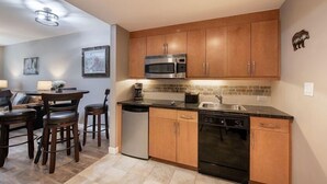 A compact kitchen with wooden cabinets, a microwave, dishwasher, and a coffee maker.