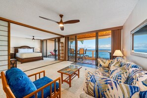A spacious room with a bed, a sofa, a coffee table, and a balcony with a view of the ocean. - Big Island Keauhou Surf & Racquet 1204 2 Bedroom Condo (Kailua-Kona)