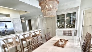 A spacious kitchen with a large island, white cabinetry, and a hanging light fixture.