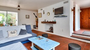 A living room with a sofa, a coffee table, a TV, and a fireplace. - Relaxation and sharing at "Sables d'Or" (La Guérinière)
