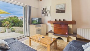 Un salon avec un téléviseur, une table basse en bois, un canapé et une cheminée.