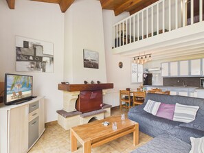 Una sala de estar con televisión, chimenea, comedor y cocina.