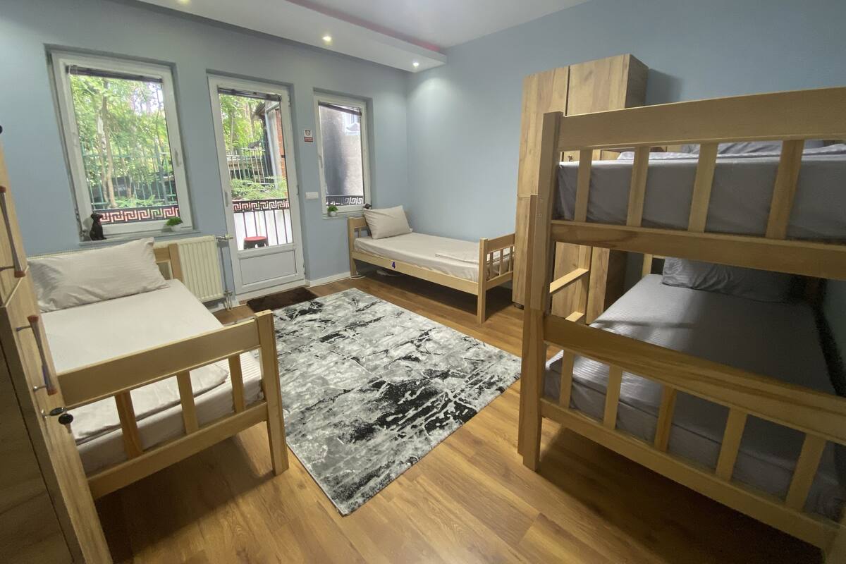 Une chambre avec deux lits superposés, un petit bureau et une fenêtre donnant sur un espace verdoyant.
