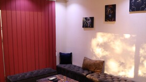 A modern living room with a red accent wall, a tufted sofa, a coffee table, and a blue armchair.