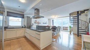 A modern kitchen with a central island, built-in appliances, and a large window. - Marys Holiday Penthouse (Saalbach-Hinterglemm)