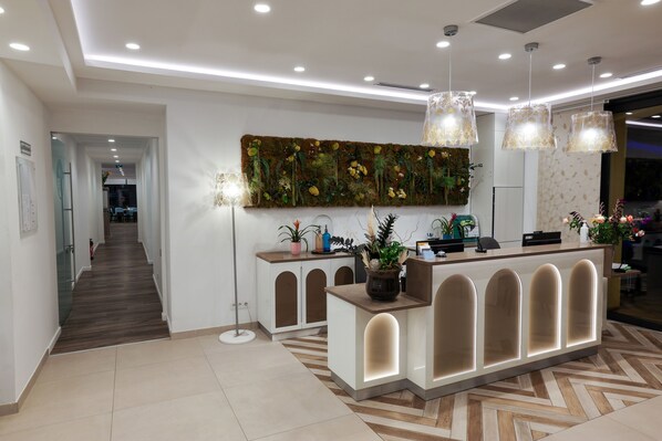Un área de recepción moderna con un mostrador de madera, un gran muro decorativo e iluminación colgante.