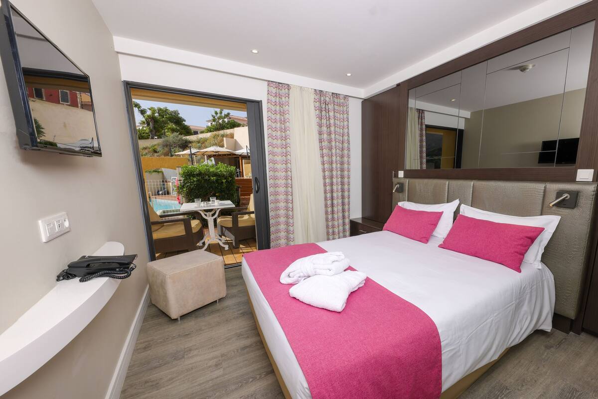 Une chambre d’hôtel moderne avec un grand lit, un petit coin salon et un balcon avec vue.