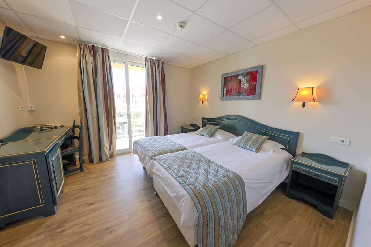 Une chambre d’hôtel avec un lit, un bureau, une chaise et un téléviseur.