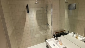 Ein modernes Badezimmer mit einer Duschkabine aus Glas, einem weißen Waschbecken mit Spiegel und einem Fliesenboden.