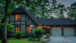A two-story house with a dark roof and white walls, a driveway, and a garage with two doors. - Rosewood Cottage Tucked Away in the Mountains (Franklin)