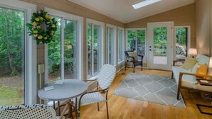 A spacious room with large windows, a round table, a sofa, and a patterned rug. - Rosewood Cottage Tucked Away in the Mountains (Franklin)