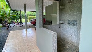 A covered outdoor area with a tiled floor, a bicycle, and a car parked nearby. - 2 Room Family Home in Bahia, Gated, walking distance to National Park (Bahia Ballena)