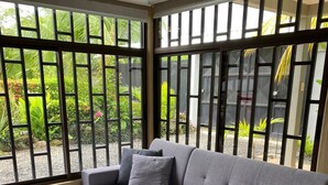 A grey sectional sofa with a matching ottoman, a striped area rug, and a view of a garden through large windows with black frames. - 2 Room Family Home in Bahia, Gated, walking distance to National Park (Bahia Ballena)