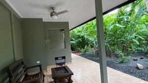 An outdoor patio with a ceiling fan, two wooden chairs, and a small table. - 2 Room Family Home in Bahia, Gated, walking distance to National Park (Bahia Ballena)