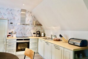 A compact kitchen with a built-in oven, a coffee maker, and a toaster on the counter.