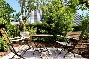 Un patio jardín con una mesa de madera y dos sillas de madera.
