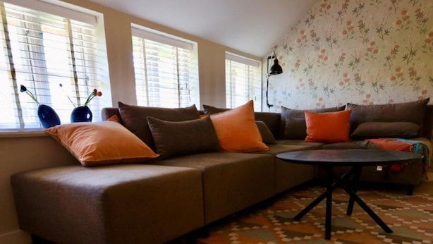 Ein Wohnzimmer mit einem Ecksofa, einem runden Couchtisch und einem gemusterten Teppich.