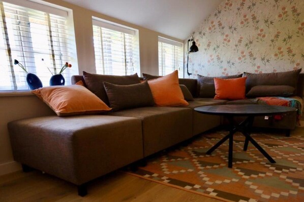 A living room with a sectional sofa, a round coffee table, and a patterned rug.