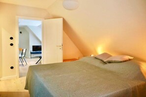 Un dormitorio con una cama, una silla y televisión en la habitación contigua.