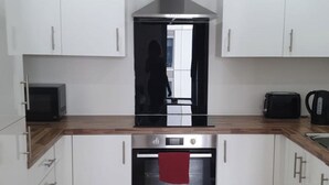 Una cocina moderna con armarios blancos, horno de acero inoxidable, microondas y tostadora.