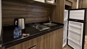 A modern kitchen with wooden cabinets, a stainless steel sink, a microwave, and a black countertop. - 1 Antica jabalal-lwebdeh (Amman)