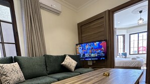 A modern living room with a sectional sofa, a wooden coffee table, and a flat-screen TV mounted on the wall. - 1 Antica jabalal-lwebdeh (Amman)
