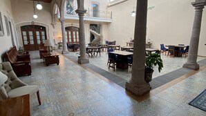 En rummelig lobby med højt til loftet, en central trappe og flere siddeområder.