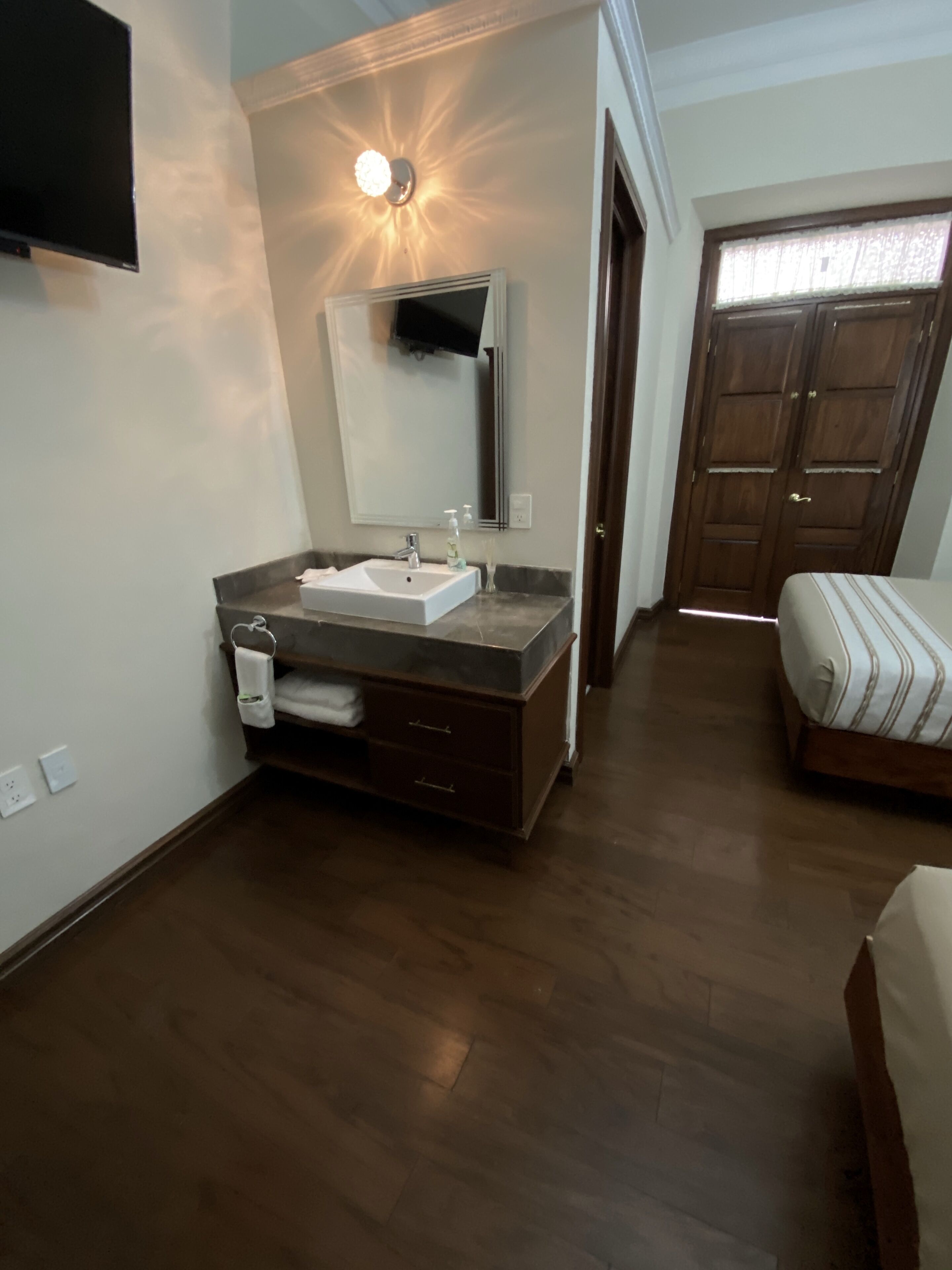 A bathroom with a sink, mirror, and wooden floor.