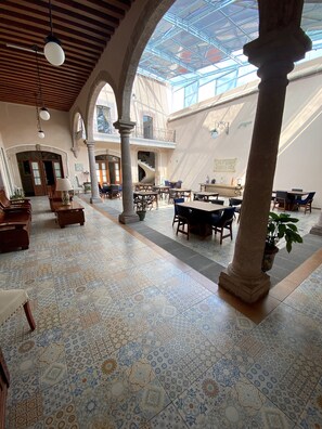 A spacious interior with high ceilings, patterned tile flooring, and a central open area with tables and chairs. - Cantera Real Hotel (Morelia)