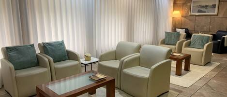 Una sala moderna con sofás color beige, una mesa de centro de vidrio y suelo de baldosas.
