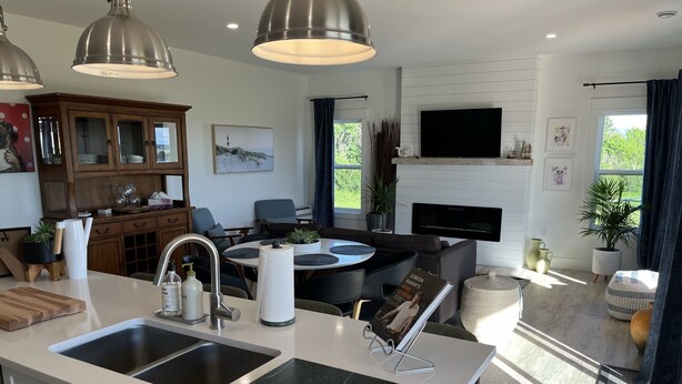 A modern kitchen with a large island, double sinks, and a dining area with a round table.