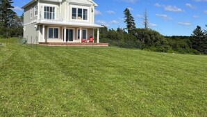 A two-story house with a front porch and a large grassy yard.