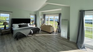 A spacious bedroom with a large bed, a ceiling fan, a sofa, and a view of the outdoors.