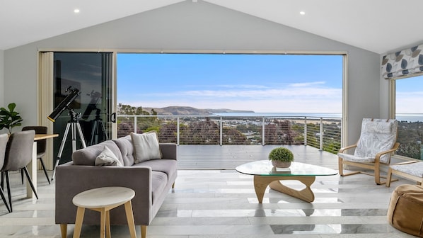 A spacious balcony with a clear view of the landscape, a comfortable seating area with a sofa and chairs, and a telescope on a tripod. - Gulf View Retreat - 11 Hewett Close (Normanville)