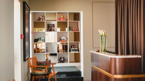 Un rincón acogedor para leer, con una estantería, un sillón de madera y una mesita.