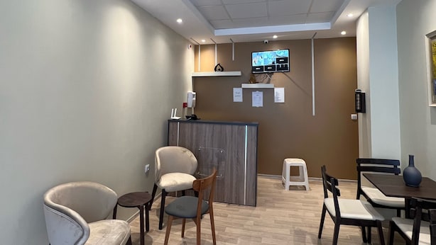 Un espace d’accueil comprenant un comptoir, des chaises, des tables et un écran de télévision.