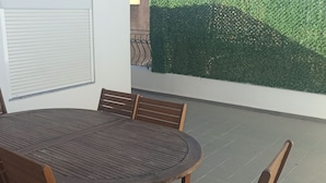 Une table ronde en bois, quatre chaises, une porte blanche et un mur végétal vert.
