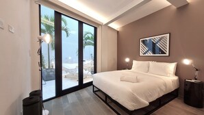 Un dormitorio moderno con una cama grande, puertas de vidrio correderas que dan a un balcón y una lámpara en el techo.