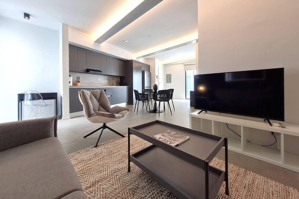 Ein modernes Wohnzimmer mit Fernseher, einer Couch und einem Couchtisch.
