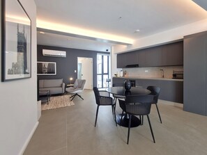A modern living room with a sofa, a dining table with chairs, and a kitchen area with cabinets and a countertop. - Lesplanade by Wynwood House (Panama City)