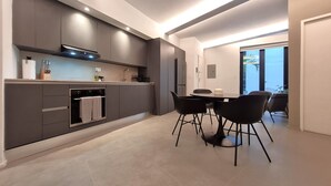 Una cocina moderna con armarios grises, horno empotrado y comedor con una mesa y cuatro sillas.