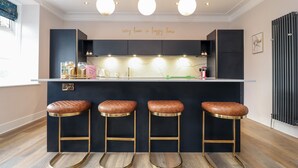 A modern kitchen with a bar area, pendant lights, and a motivational quote on the wall.