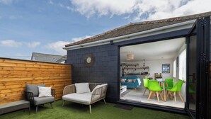 A modern house with a patio area featuring a sofa, chairs, and a dining set. - La Casita - 2-bed House in Newquay (Newquay)