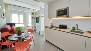 A modern kitchen with a microwave, sink, and countertop. There is a dining area with orange chairs and a table. - New apartment Central Station Milan (Milano)
