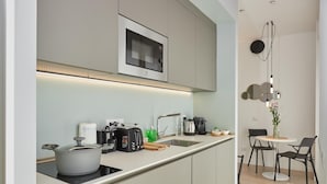 A modern kitchen with a built-in microwave, a sink, and a dining area with two chairs and a table. - Circular Apartment . (Milano)
