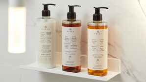 Trois bouteilles de shampoing PRIJA sur une étagère blanche.