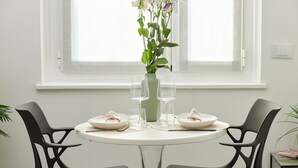 A round dining table with two black chairs, a vase with flowers, and empty wine glasses. - Luxury apartment in the center of Milan - NEW (Milano)